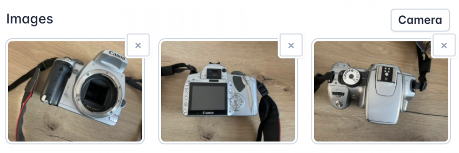 A set of three images showing different angles of a silver Canon camera with a black strap. The first image displays the front view with the lens removed, exposing the sensor. The second image captures the back of the camera, showing the LCD screen and control buttons. The third image presents a top-down view, highlighting the mode dial and shutter button. Each image has a small 'X' button for removal, and a 'Camera' button is visible for capturing additional photos.